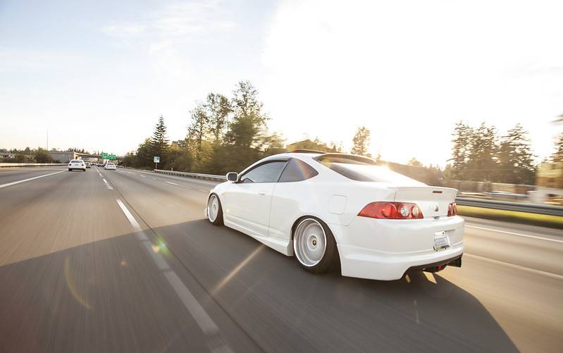 White car on highway from behind with sunny sky